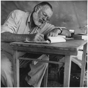 330px Ernest Hemingway Writing at Campsite in Kenya NARA 192655